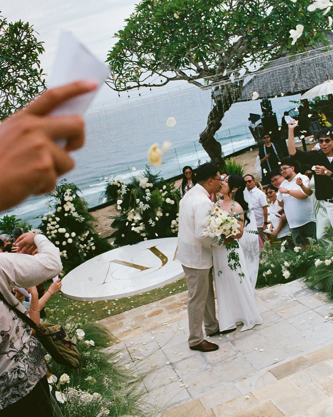 Beachfront wedding ceremony with white floral decoration and ocean backdrop